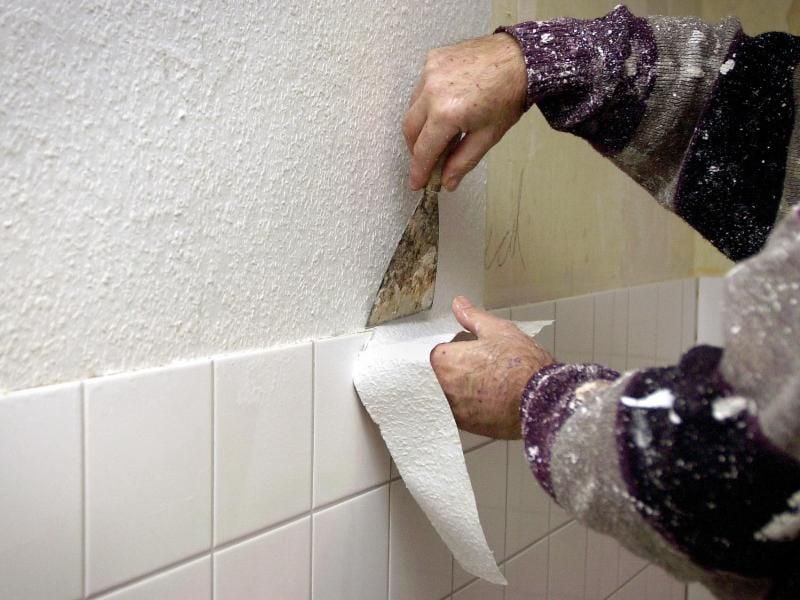 Ein Tapezierer passt die Tapete an. Mieter müssen Handwerker in die Wohnung lassen, wenn diese im Auftrag des Vermieters notwendige Instandsetzungsarbeiten vornehmen wollen. Foto: Oliver Stratmann/dpa