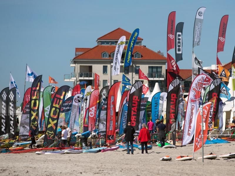 Flaggen verschiedener Surfgerätehersteller wehen am Strand der Ostsee. Foto: Axel Heimken/Archiv