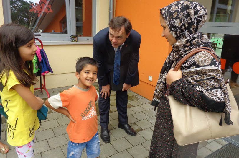 Bürgermeister Michael Jahn (SPD) spricht in der Kindertagesstätte Holzdorf mit einer Flüchtlingsfamilie aus Afghanistan.