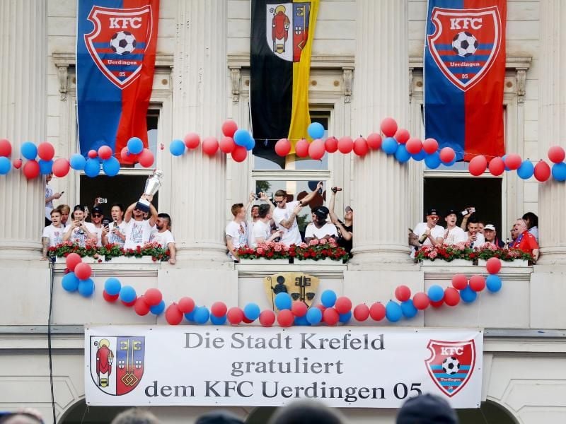 Die Uerdinger Mannschaft feiert mit dem Meisterpokal der Regionalliga West am Rathaus den Aufstieg in die 3. Liga. Foto: R. Weihrauch