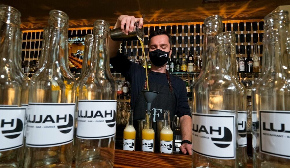 Inhaber André Hamann steht hinter der Bar im „Lujah“. Die Cocktails To-Go füllt er in Flaschen ab und verkorkt sie.