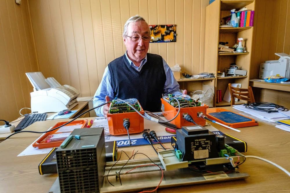 Harald Müller in seinem Büro, vor ihm die verschiedenen Steuerungen für Tagebaugroßgeräte