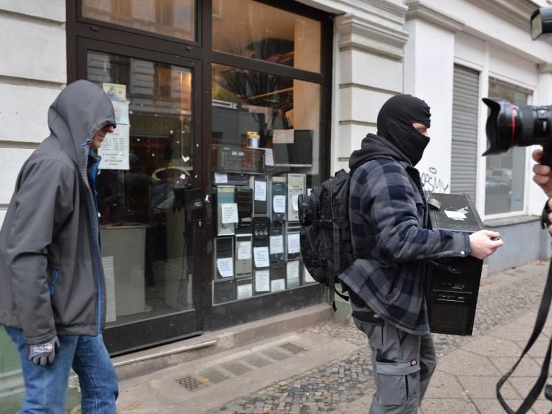 Während einer Razzia bei Reichsbürgern in Berlin trägt ein Polizist einen Computer aus einem Haus im Ortsteil Moabit. Foto: Paul Zinken