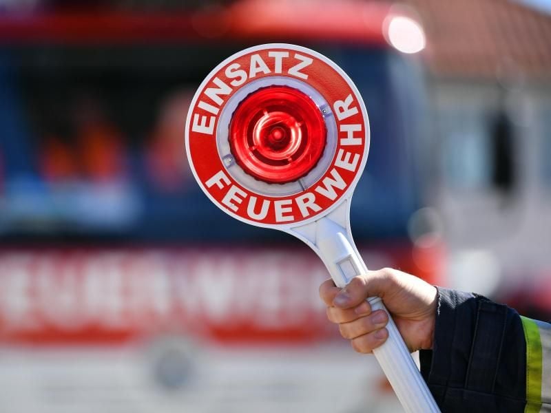 Ein Feuerwehrmann hält eine Winkerkelle mit der Aufschrift „Einsatz Feuerwehr”. Foto: Martin Schutt/dpa-Zentralbild/dpa/Symbolbild