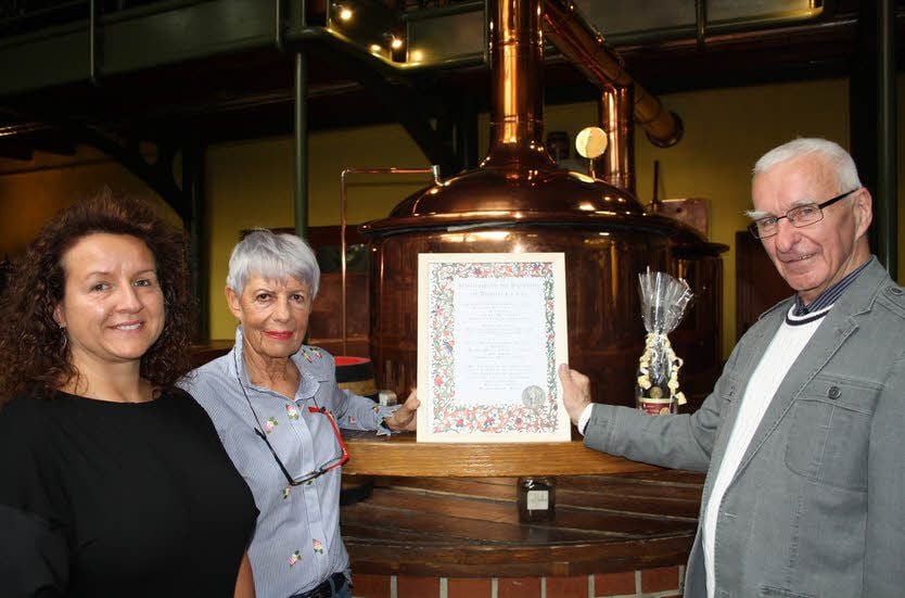Rüdiger Mertsch hat die Geburtsurkunde für den Gründer des Brauhauses Lüdde mit Doreen Post (l.) an Brauhaus-Inhaberin Eta Clair übergeben.
