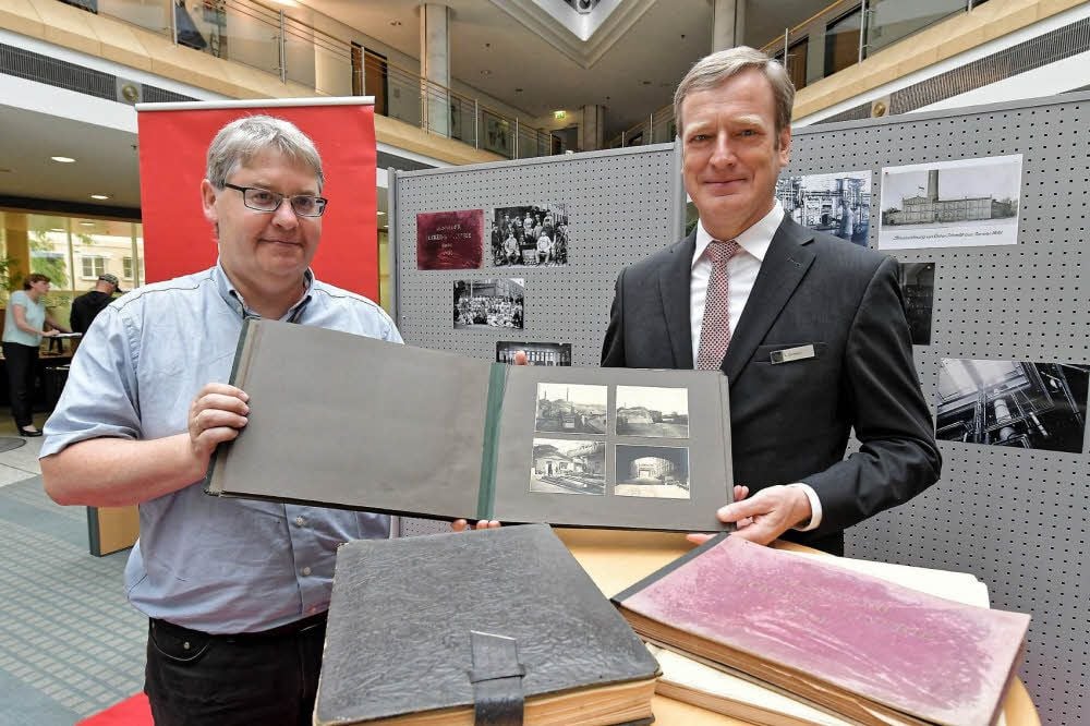 Stadtarchivleiter Frank Kreißler (l.) und Sparkassenvorstand Konrad Dormeier zeigen stolz die fünf Alben zur Zuckerraffinerie.