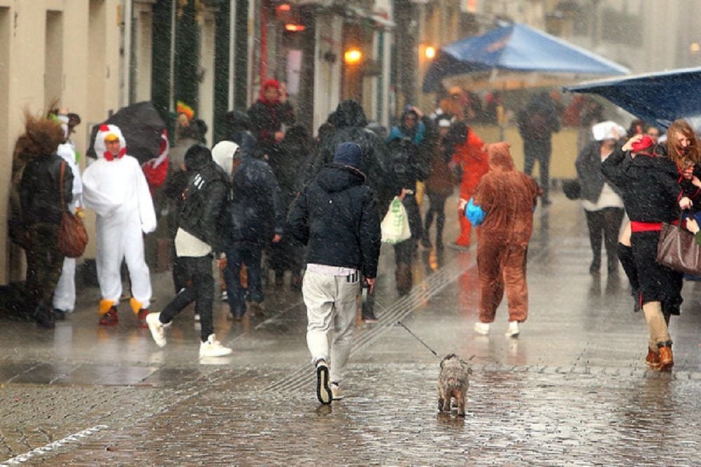 Narren flüchten am Rosenmontag 2016 in Düsseldorf vor Regen und Sturm.