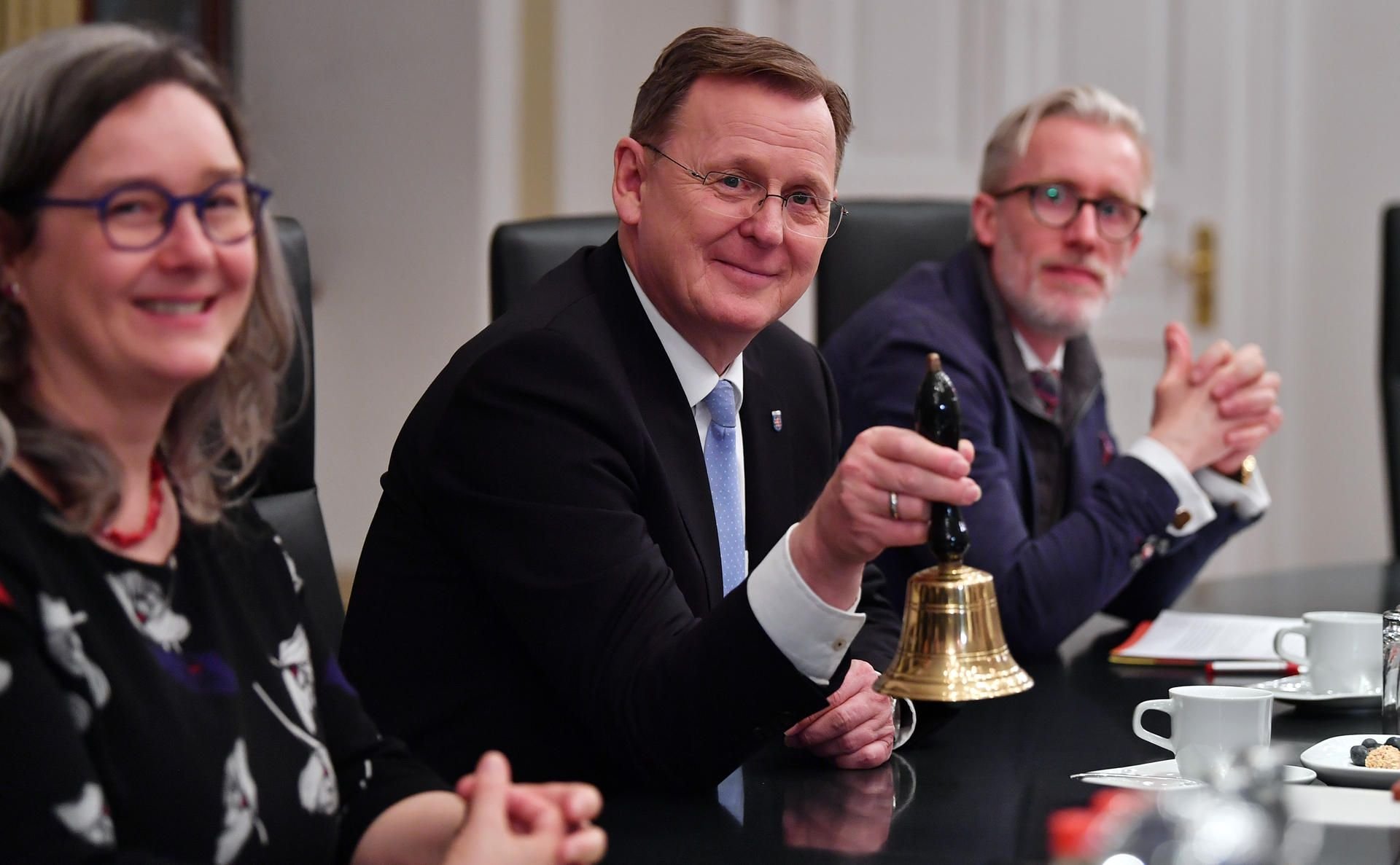 Heike Werner (Die Linke, l.), Sozialministerin von Thüringen, Bodo Ramelow (Die Linke, M.), Ministerpräsident von Thüringen mit Glocke und Staatskanzleichef Benjamin-Immanuel Hoff (Die Linke, r.) sitzen zur ersten Kabinettsitzung zusammen.