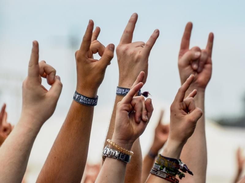 Besucher des Wacken Open Air feiern Auftritt der lokalen Feuerwehrkapelle mit dem Metalgruß, der „Pommesgabel”. Foto: Axel Heimken/Archiv