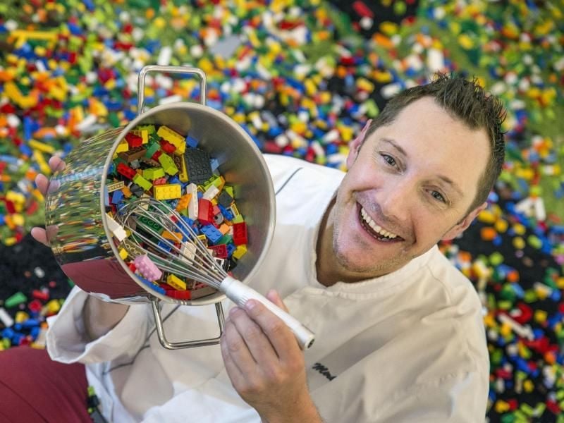 Mirko Reeh sitzt zwischen Legosteinen mit einem Kochtopf in der Hand. Foto: Andreas Arnold/Archiv