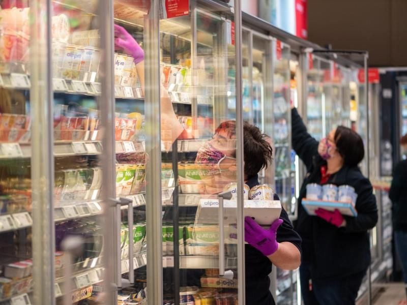 Mitarbeiterinnen in einem Supermarkt bestücken die Regale mit Waren. Foto: Robert Michael/dpa-Zentralbild/dpa
