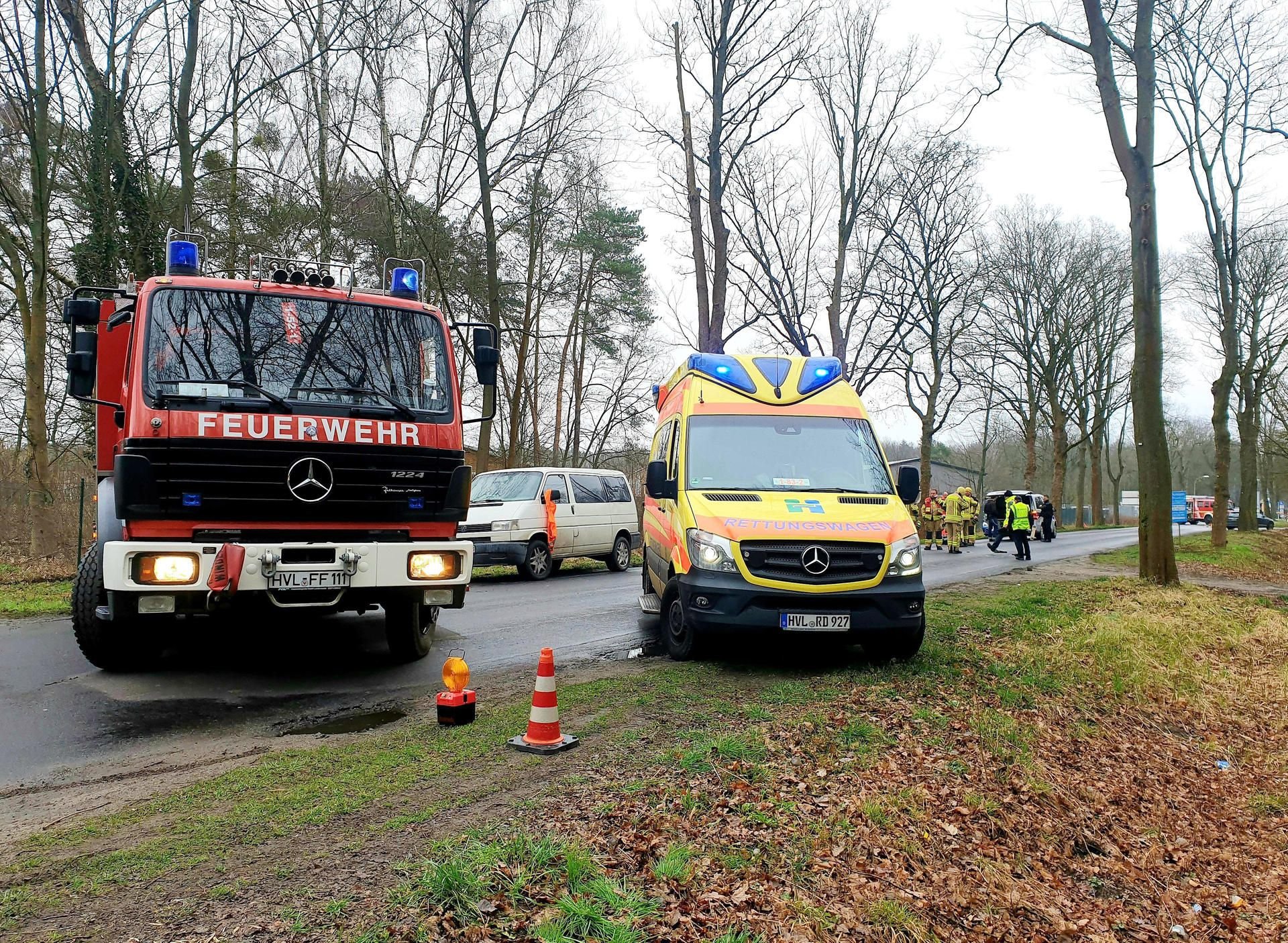 Einsatzfahrzeuge von Feuerwehr und Krankenwagen sowie Einsatzkräfte stehen nach einem Verkehrsunfall in Falkensee am Unfallort.