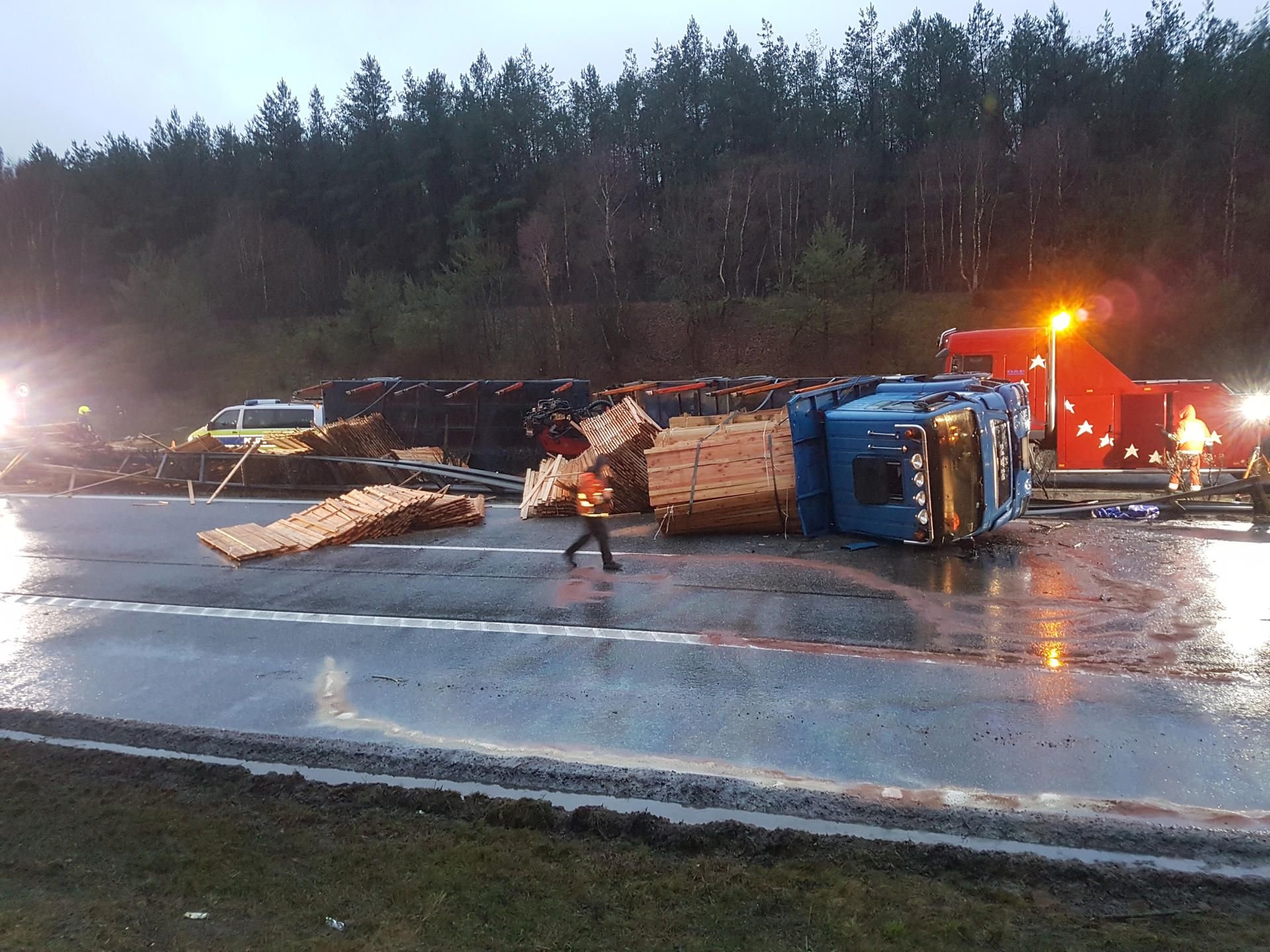 Ein mit Holz beladener Lastwagen liegt am Dienstag auf der Mittelleitplanke der Autobahn A24 bei Stolpe.