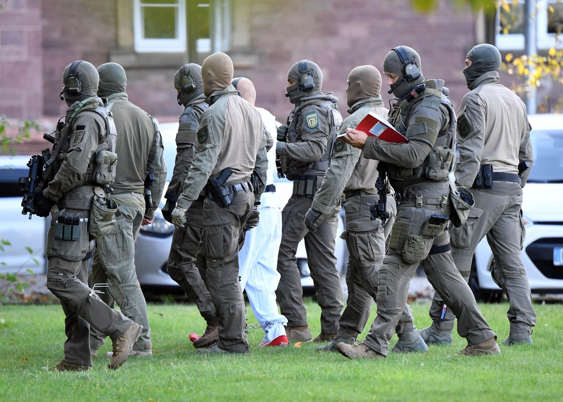 Der mutmaßliche Rechtsextremist Stephan B. (in weißem Overall) wird von Polizisten in Karlsruhe aus einem Hubschrauber gebracht.