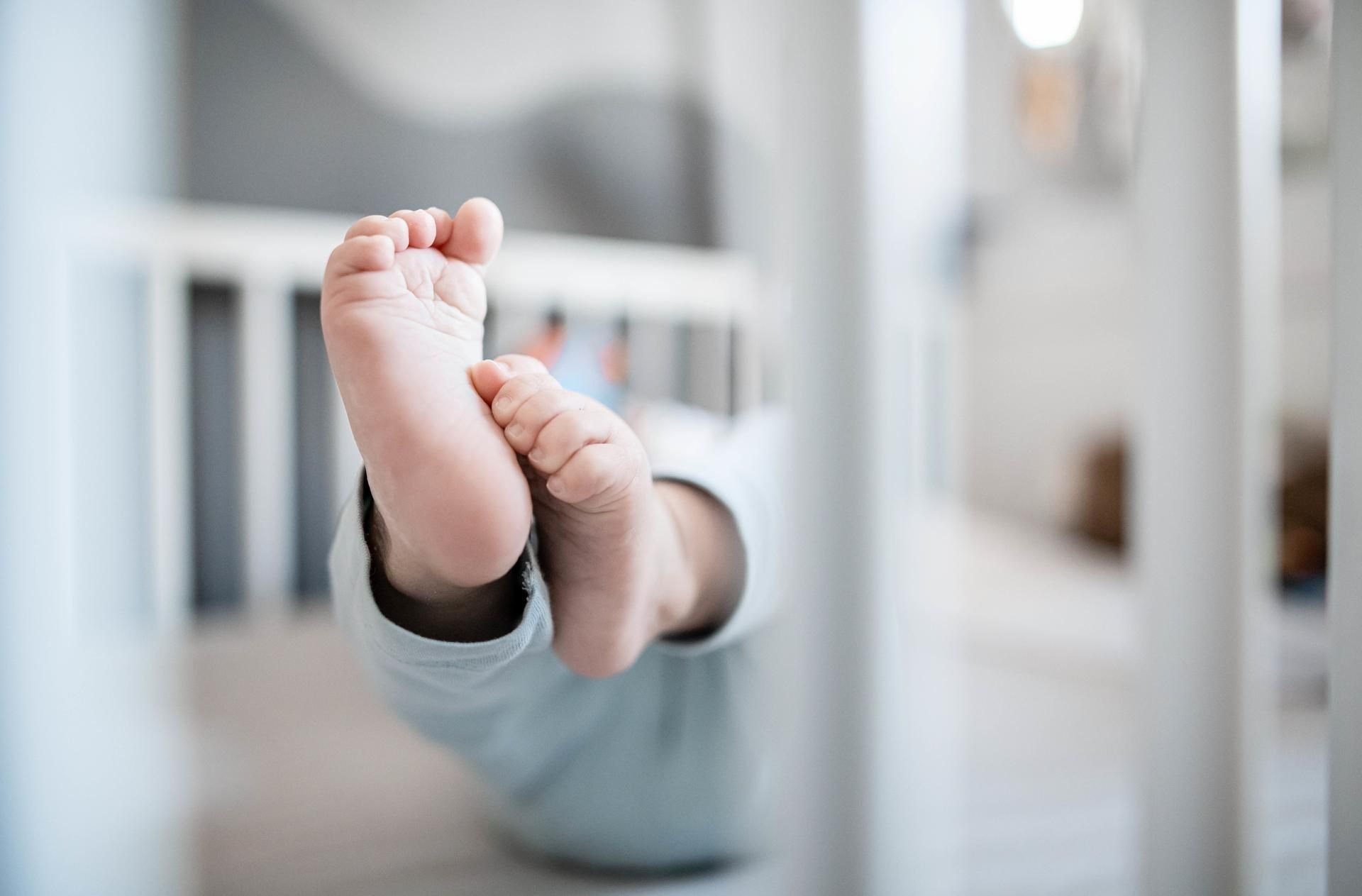 Die Füße eines Babys sind in einem Kinderbett zu sehen. Die beliebtesten Babynamen werden jedes Jahr von der Gesellschaft für deutsche Sprache (GfdS) bekannt gegeben.