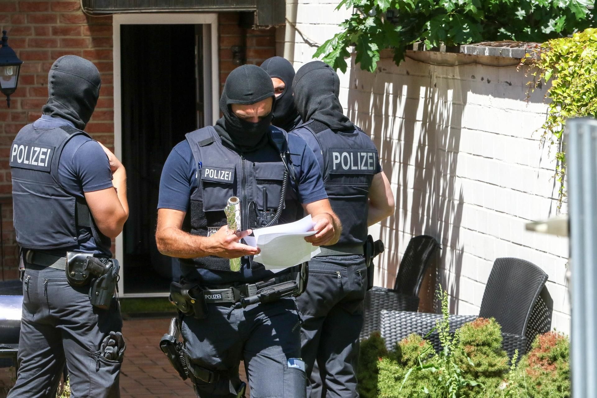 Polizisten durchsuchen den Hinterhof eines Hauses (Symbolbild)