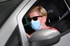 Eine Frau trägt beim Autofahren einen Mundschutz. (Symbolbild)
