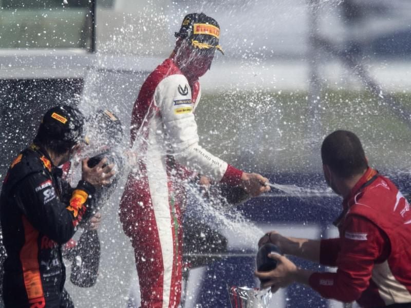 Formel-2-Pilot Mick Schumacher (M) feiert seinen Sieg in Sotschi mit Champagner. Foto: Pavel Golovkin/Pool AP/dpa