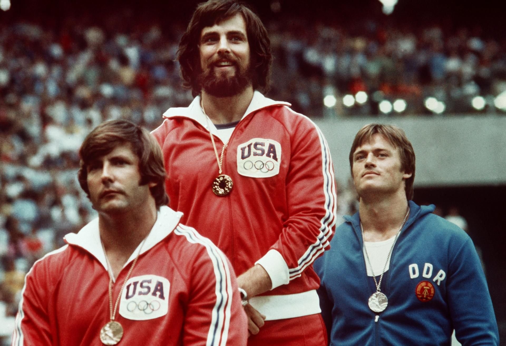 25.07.1976, Kanada, Montreal: Siegerehrung für die besten Diskuswerfer bei den Olympischen Sommerspielen. Mac Wilkins (M., USA) gewinnt Gold vor DDR-Werfer Wolfgang Schmidt (r.) und John Powell (l., USA).