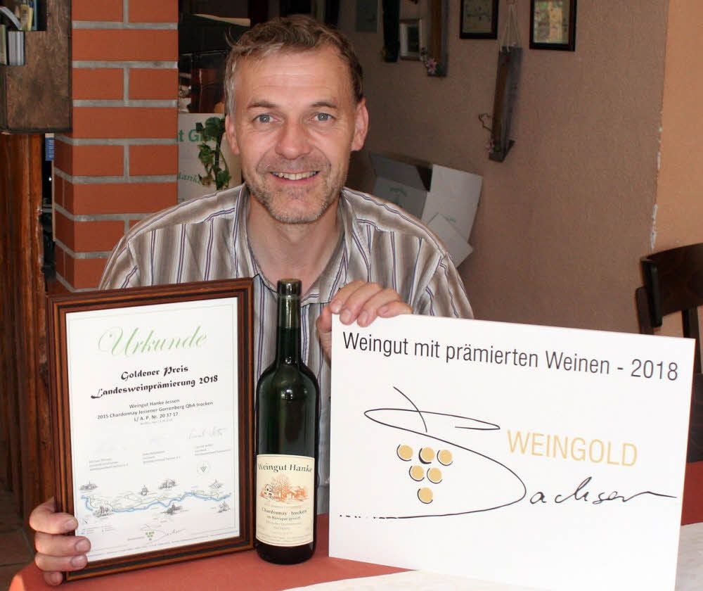 Der Jessener Winzer Ingo Hanke mit seinem bei der Sächsischen Landesweinprämierung 2018 vergoldeten Chardonnay, im Barrique gereift, trocken, und der zugehörigen Urkunde plus Weingut-Schild