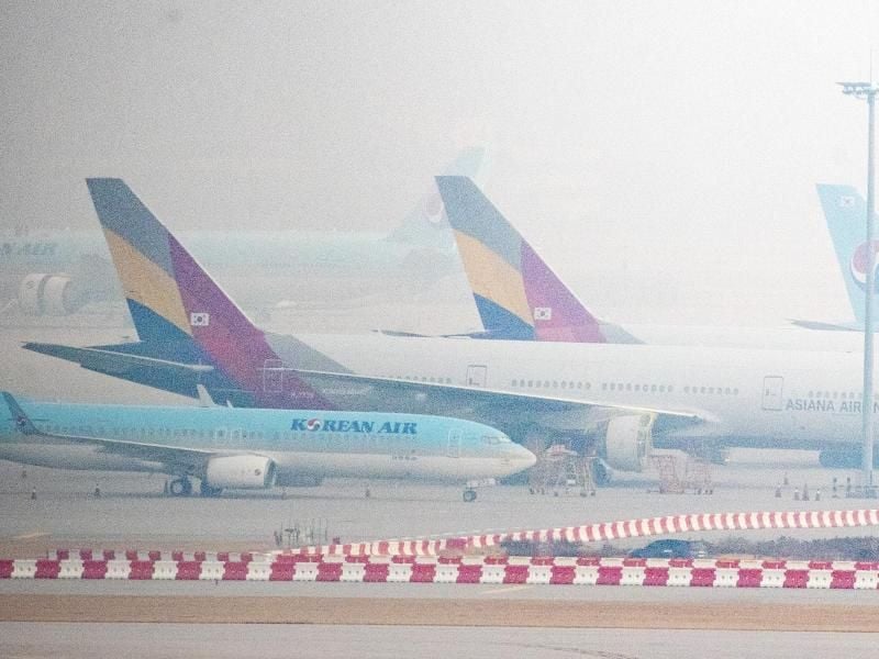 Flugzeuge der Fluggesellschaften Korean Air und Asiana Airlines stehen bei nebeligem Wetter nebeneinander am Flughafen „Incheon International Airport” westlich von Seoul. Foto: -/YNA/dpa