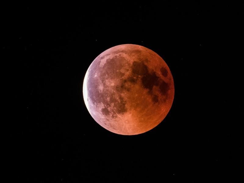 Der teilweise vom Erdschatten verdunkelte Vollmond leuchtet während einer Mondfinsternis rot bis orange. Foto: Silas Stein/Archiv