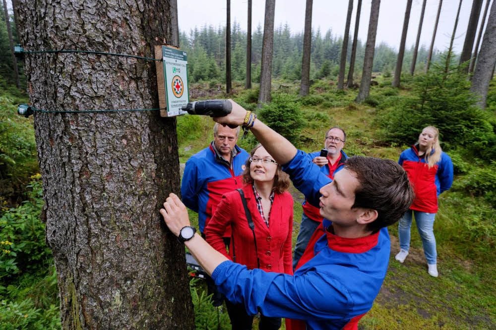 Simon George befestigt das Schild, beobachtet von Isabel Reuter (v.) und Bergwacht-Kollegen.