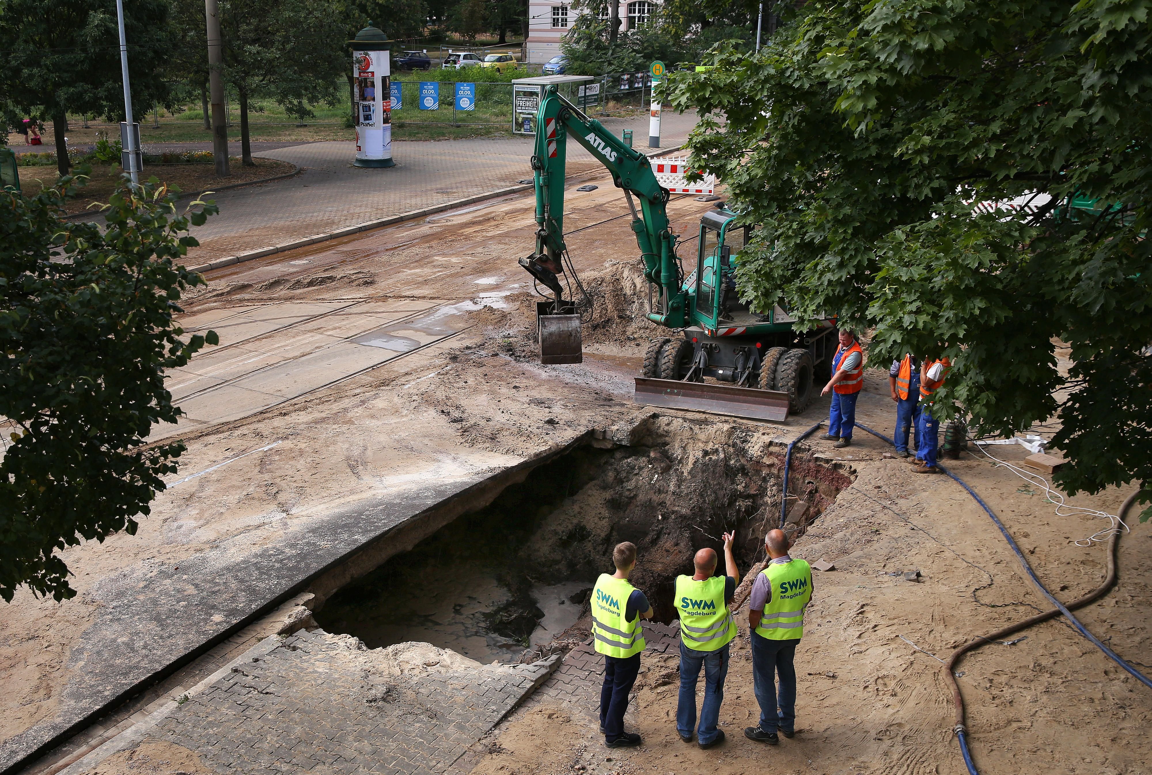 Mitarbeiter der Städtischen Werke Magdeburg (SWM) stehen in Magdeburg vor dem Landgericht an einem mehrere Quadratmeter grossen Loch im Gehweg, das durch einen Wasserrohrbruch entstanden ist.