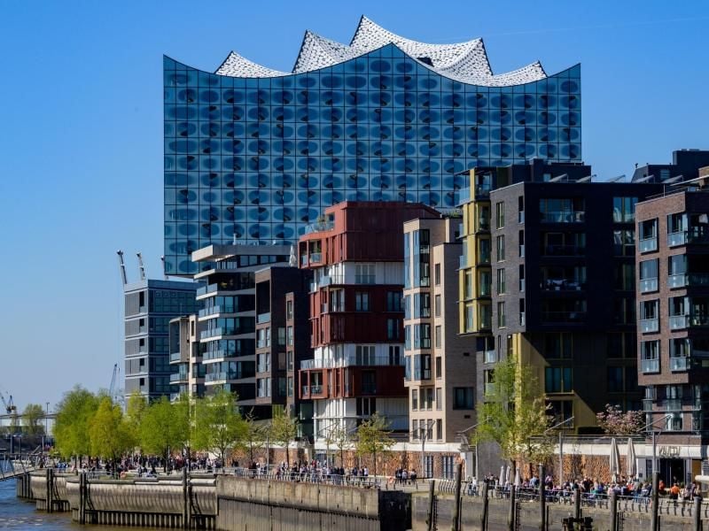 Besucher der Hafencity schlendern am Kaiserkai entlang - im Hintergrund ist die Elbphilharmonie zu sehen. Foto: Axel Heimken/Archivbild
