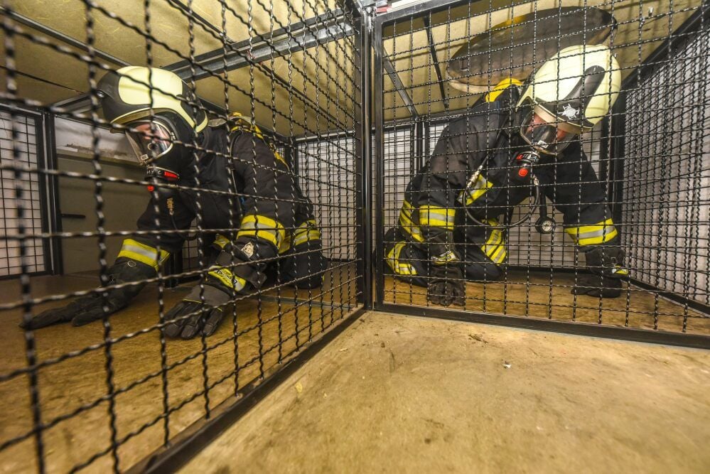 Kriechend geht es für die beiden Feuerwehrmänner aus Großkayna unter Atemschutz durch die Käfige.