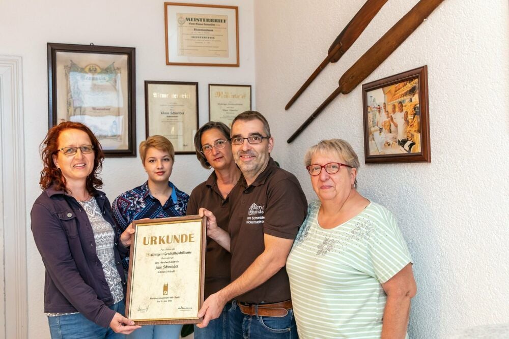 Elke Kolb von der Handwerkskammer überreicht Jens Schneider die Jubiläums-Urkunde. Mit im Bild: Schneiders Mutter Dorothea (r), dazu Ehefrau Birgit und Tochter Victoria.