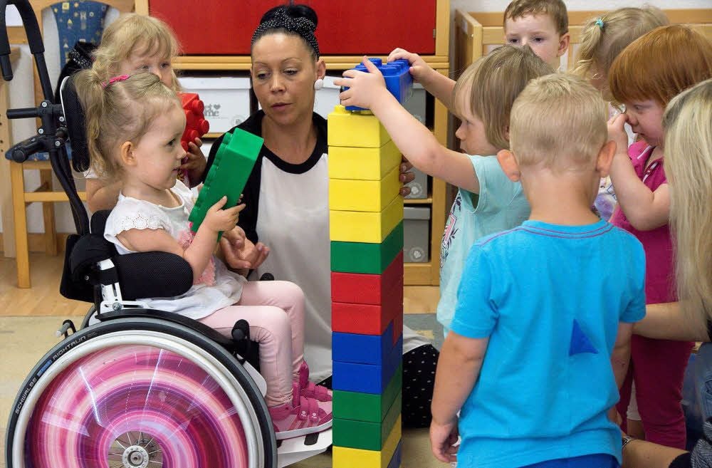 Claras Mobilitäts-Assistentin Bianca Berger fasst zu, wenn ihr Schützling Probleme hat, beispielsweise beim Spielen mit Bausteinen.