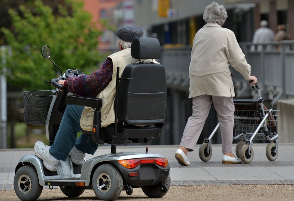 Ein Mann ist mit einem Elektrorollstuhl (E-Rolli) unterwegs.