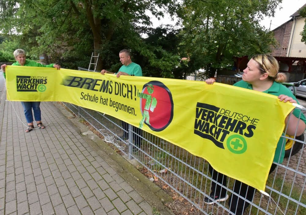 Petra Poprawe, Rüdiger Hauer und Mandy Kluge (von links) von der Verkehrswacht Hohenmölsen Teuchern bringen am Bauhof Teuchern das Spruchband an. Die Botschaft ist klar: Vorsicht, die Schule beginnt.