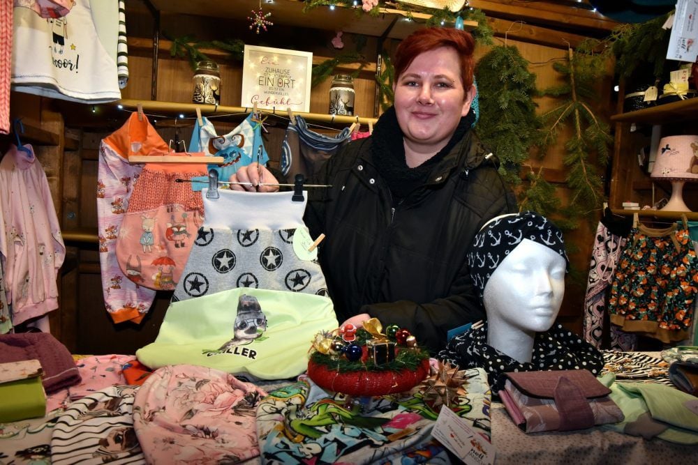 Peggy Franke zeigt Kleidungsstücke, die sie an ihrem Stand auf dem Weißenfelser Weihnachtsmarkt anbietet.