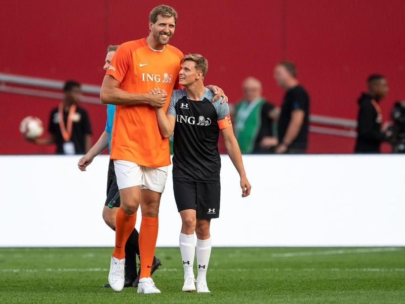 Dirk Nowitzki (l) und Mick Schumacher klatschen sich während der Partie ab. Foto: Marius Becker