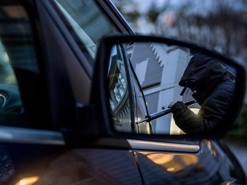 Ein Mann versucht eine Autotür mit einer Metallstange aufzubrechen. Foto: Axel Heimken/dpa/Illustration