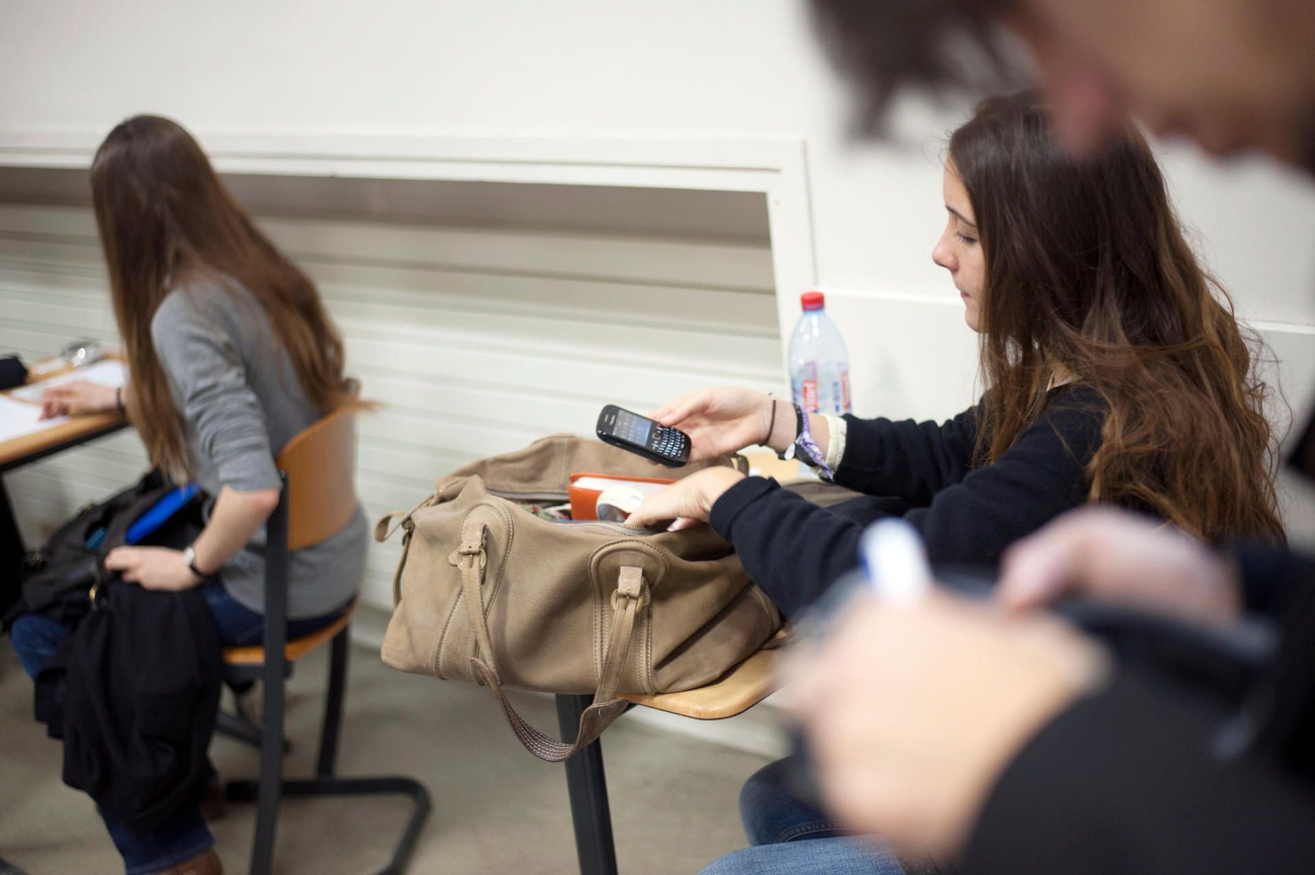 Eine Schülerin packt ihr Handy im Kalssenraum in die Tasche.
