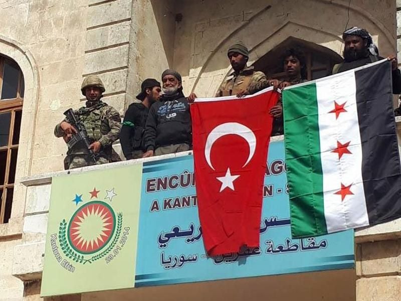 Ein türkischer und ein von der Türkei unterstützter Soldat der Freien Syrischen Armee (FSA) halten eine türkische und eine FSA-Flagge im Stadtzentrum von Afrin. Foto: Hasan Kirmizitas/DHA-Depo Photo/AP/