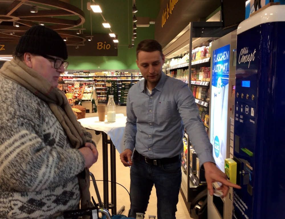 Die erste Milchtankstelle in Zeitz ist im neuen Edeka-Markt in Betrieb. Philipp Schulz (rechts) von der Agrargenossenschaft Prießen erklärt Frank Gerhardt, wie es funktioniert.