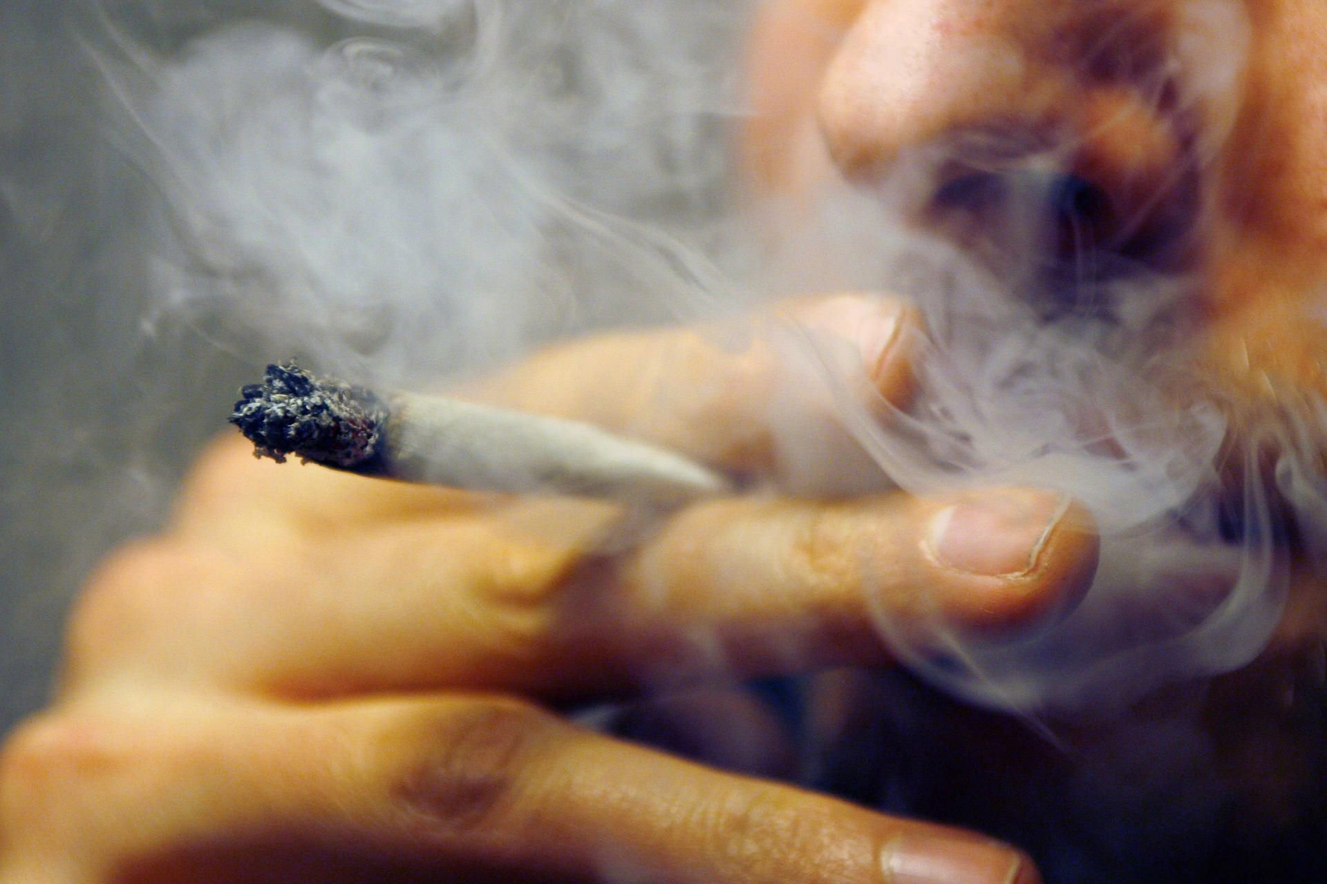 Ein Mann raucht einen Joint, eine mit Haschisch oder Marihuana versetzte Zigarette.