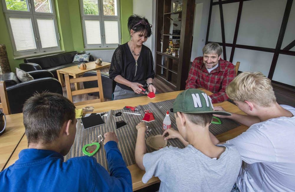 Drei Jungen basteln mit Heilerziehungspflegerin Daniella Binnemann. Lutz Kaufhold, der Leiter des Kinder- und Jugendheims Gernrode, schaut ihnen dabei zu.
