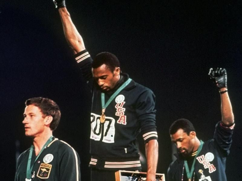 Tommie Smith (M) und John Carlos strecken 1968 bei der Siegerehrung die Fäuste nach oben. Links der australische Silbermedaillengewinner Peter Norman. Foto: Anonymous/AP