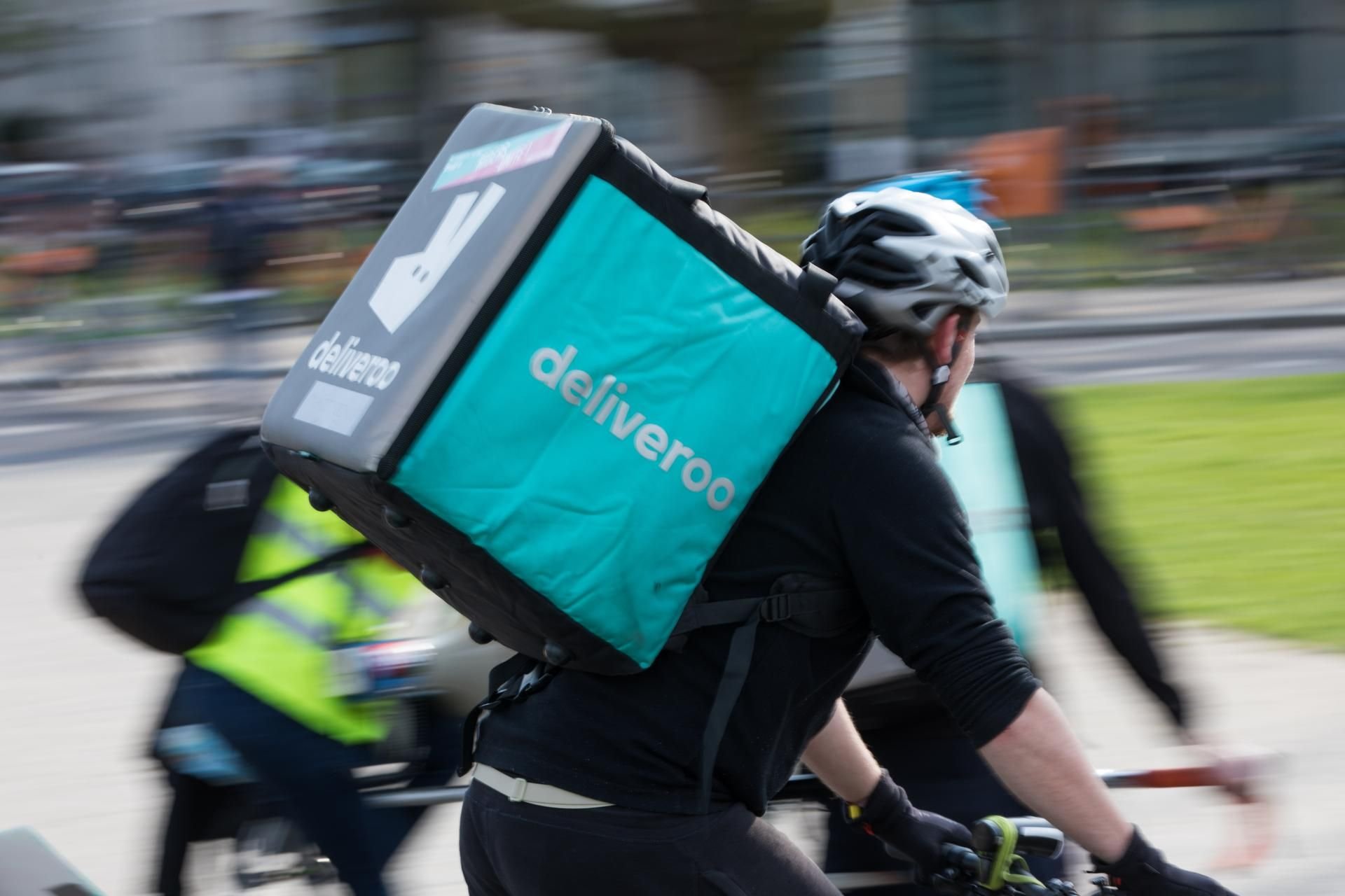 Ein Teilnehmer der Kundgebung des Vereins «Aktion gegen Arbeitsunrecht» gegen schlechte Arbeitsbedingungen beim Essenslieferdienst «Deliveroo» fährt mit einer Deliveroo-Auslieferungsbox durch die Stadt.