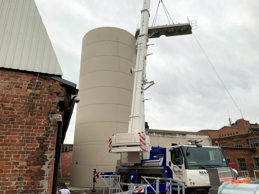 Aus gebogenen Betonsegmenten wird der Turm als Spänesilo im Hof hinter der Produktionshalle aufgebaut. Inzwischen ist er fertig.