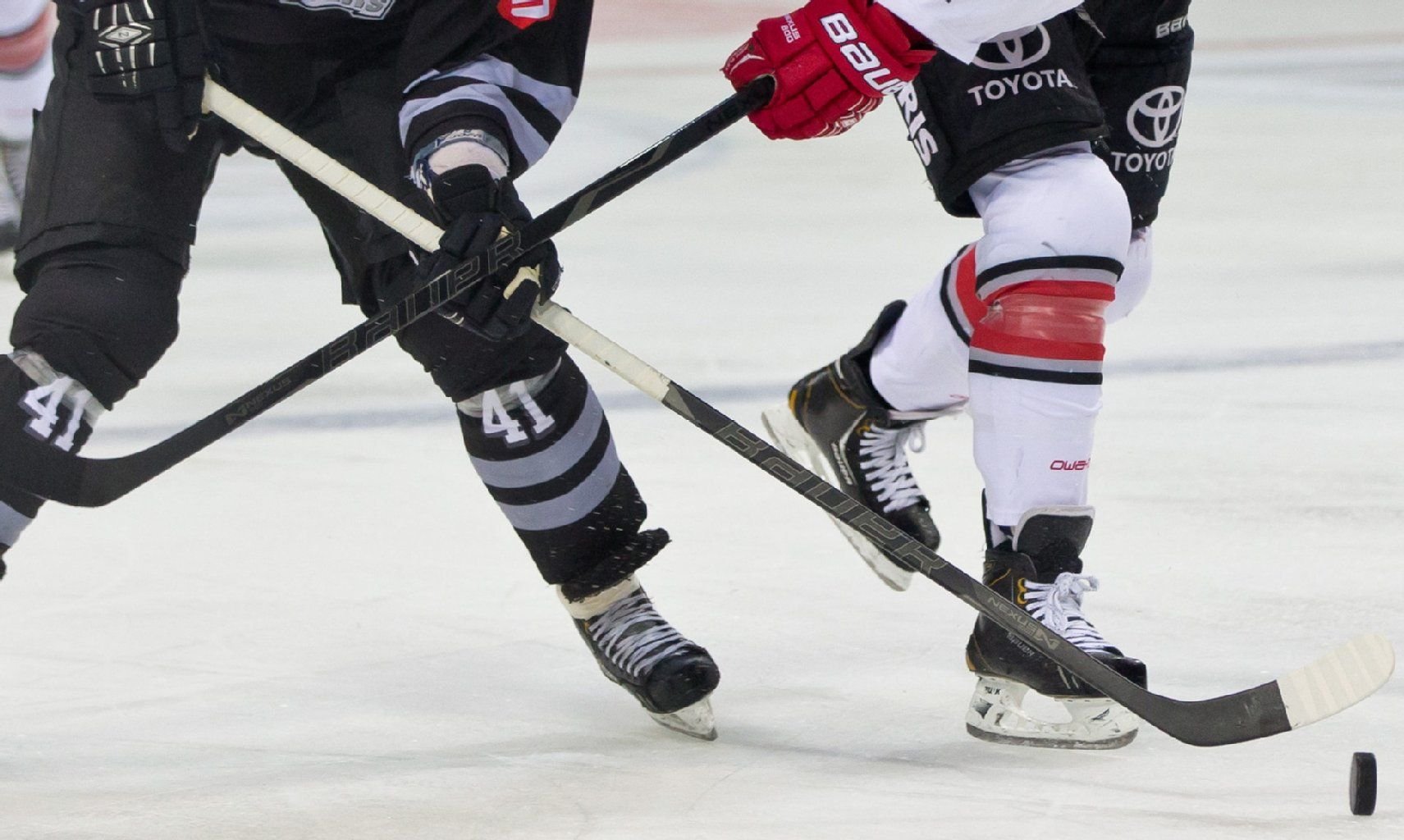 Zwei Eishockeyspieler kämpfen um den Puck.