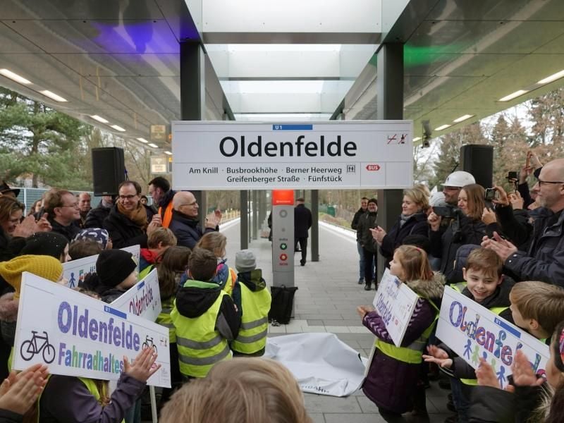 Peter Tschentscher (SPD, hinten Mitte l.) steht mit Mitarbeitern der Hamburger Hochbahn und Kindern. Foto: Tim Vogel/dpa
