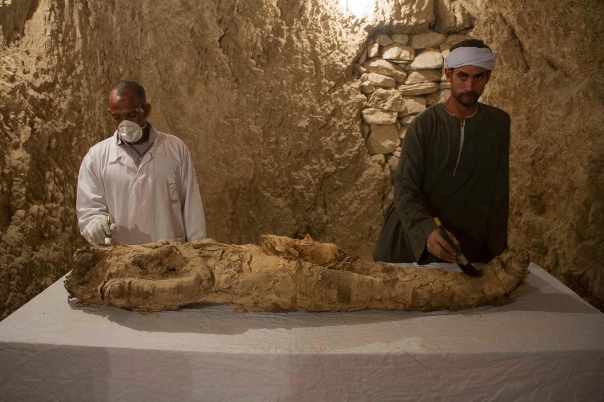 Ägyptische Ausgrabungshelfer restaurieren eine der Mumien aus den neu entdeckten Grabkammern in Luxor.