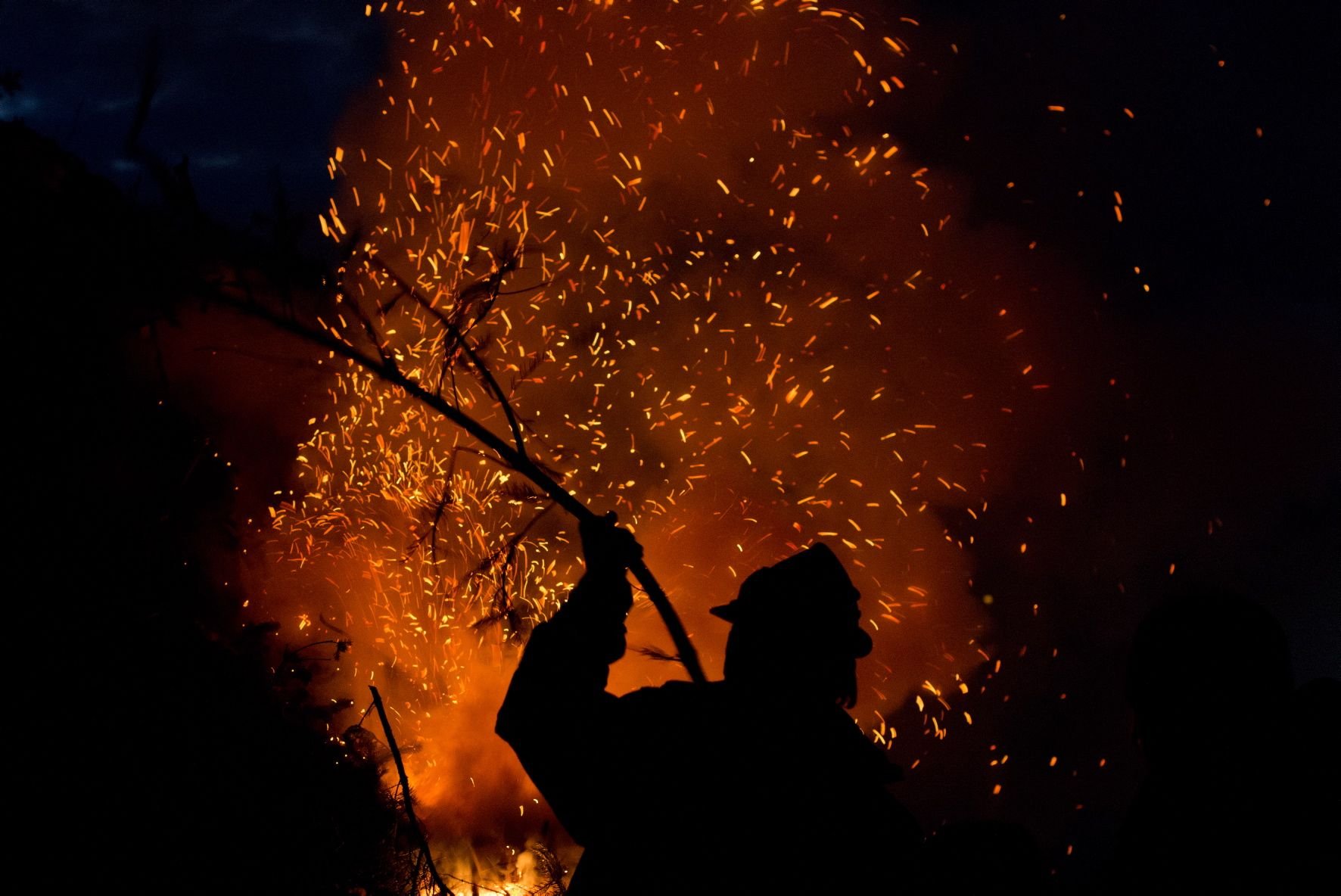 Ein Mann wirft bei einem Osterfeuer im Harz einen Stock in die lodernden Flammen.