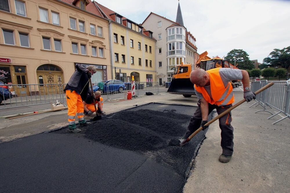 Mitarbeiter des Bauwirtschaftshofes aus Aschersleben brachten am Dienstag über dem verfüllten Hohlraum Bitumen auf.